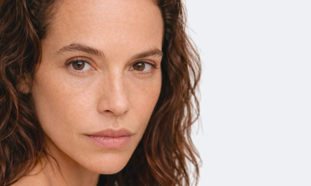 Portrait d’une femme à la peau mature avec un teint naturel, illustrant les préoccupations liées aux signes de l’âge, au manque d’éclat et aux taches pigmentaires.