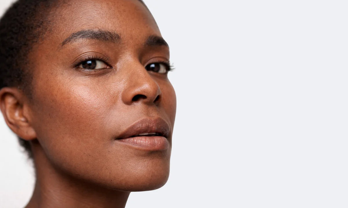 Gros plan d’un visage féminin à la peau lumineuse, illustrant les besoins des peaux déshydratées et sujettes aux rougeurs, avec un teint hydraté et uniforme.